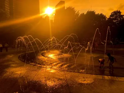 Children playing in a fountain at sunset