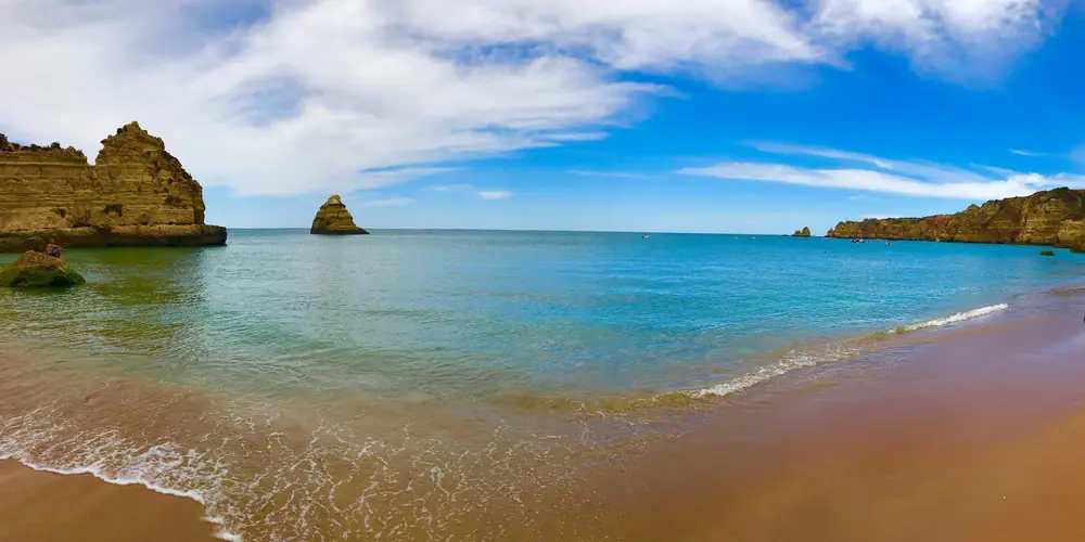 Turquoise surf running up a wide sand beach