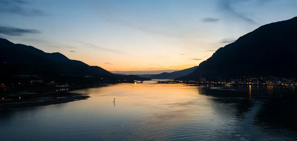 Town lights strung along a fjord at dusk