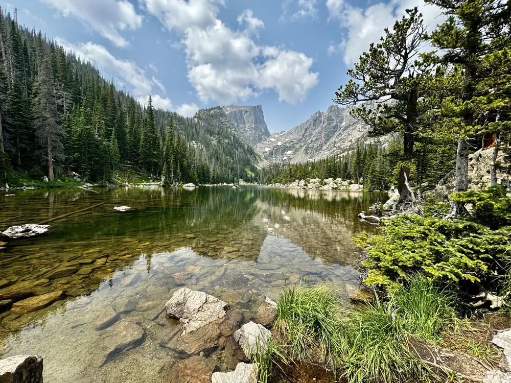 Alpine lake below granite peaks, clear water over pale stones