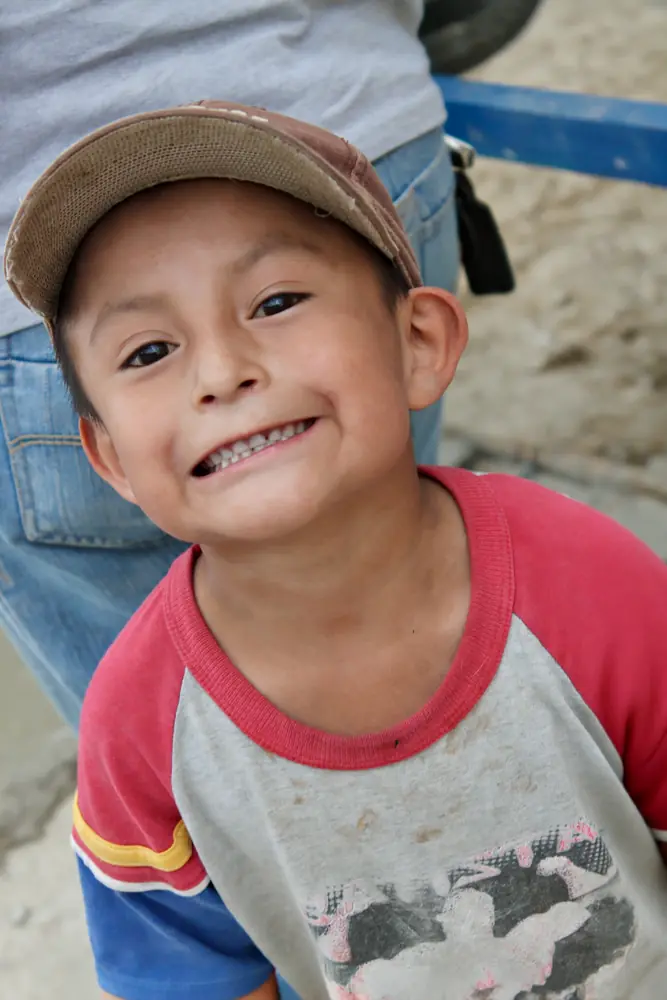 Boy in a cap grinning, arms at his sides