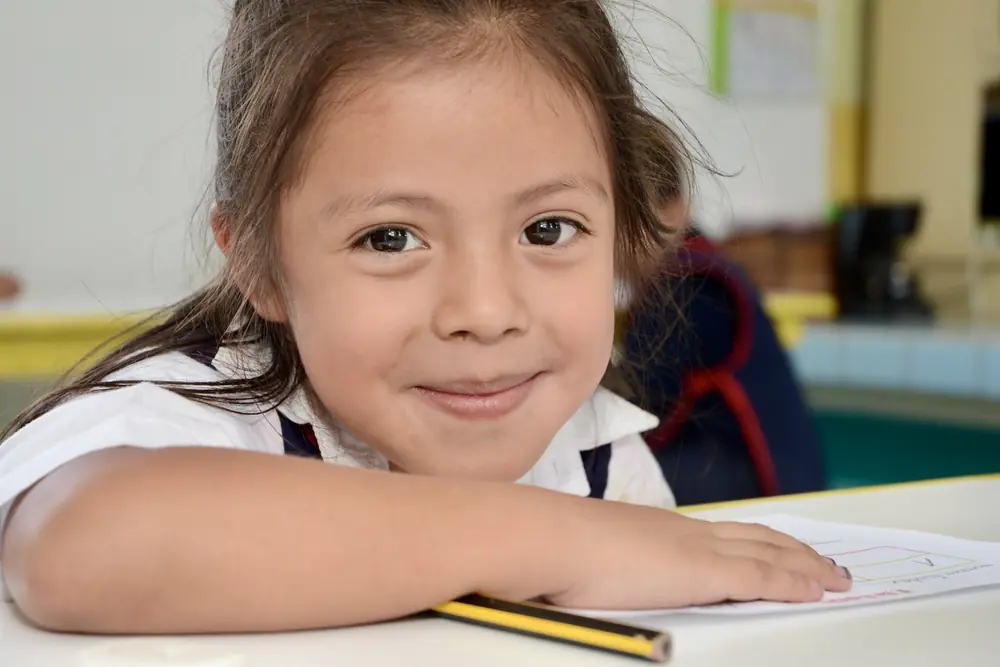 Girl at a classroom desk, pencil in hand