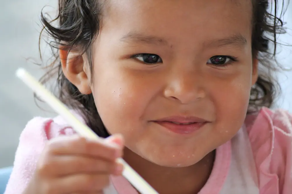 Small girl holding a straw, curls around her face