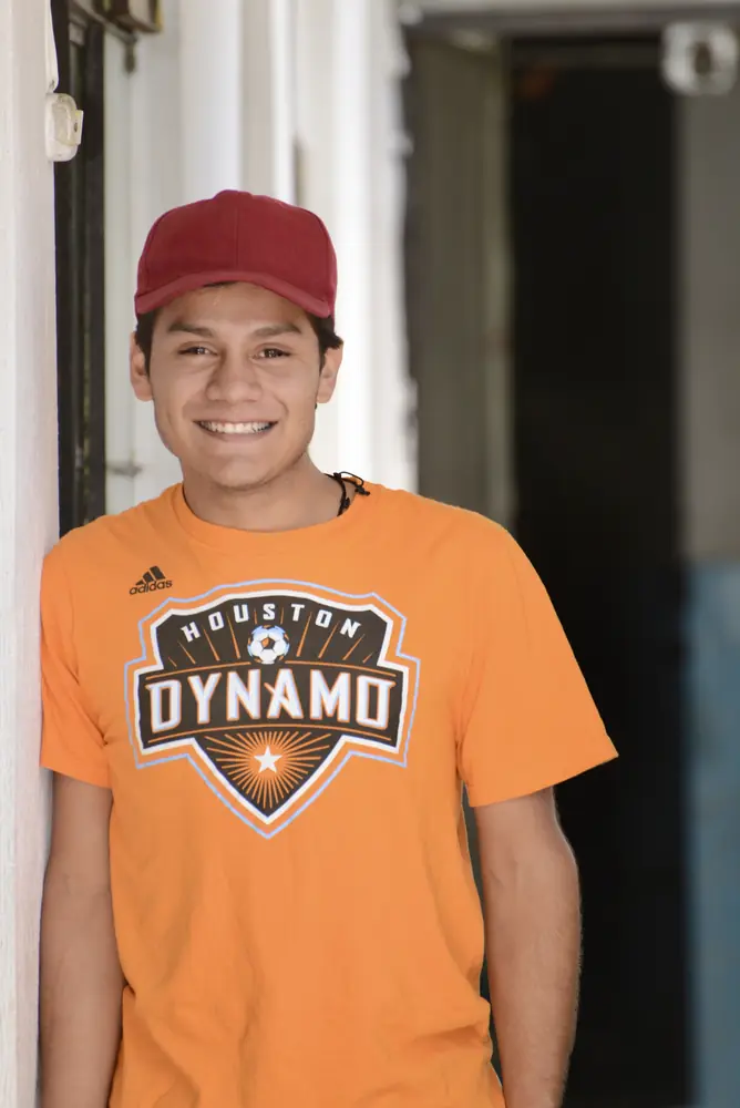 Teenager leaning in a doorway in an orange jersey