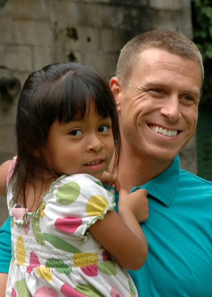 A man holding a young girl who leans into his shoulder