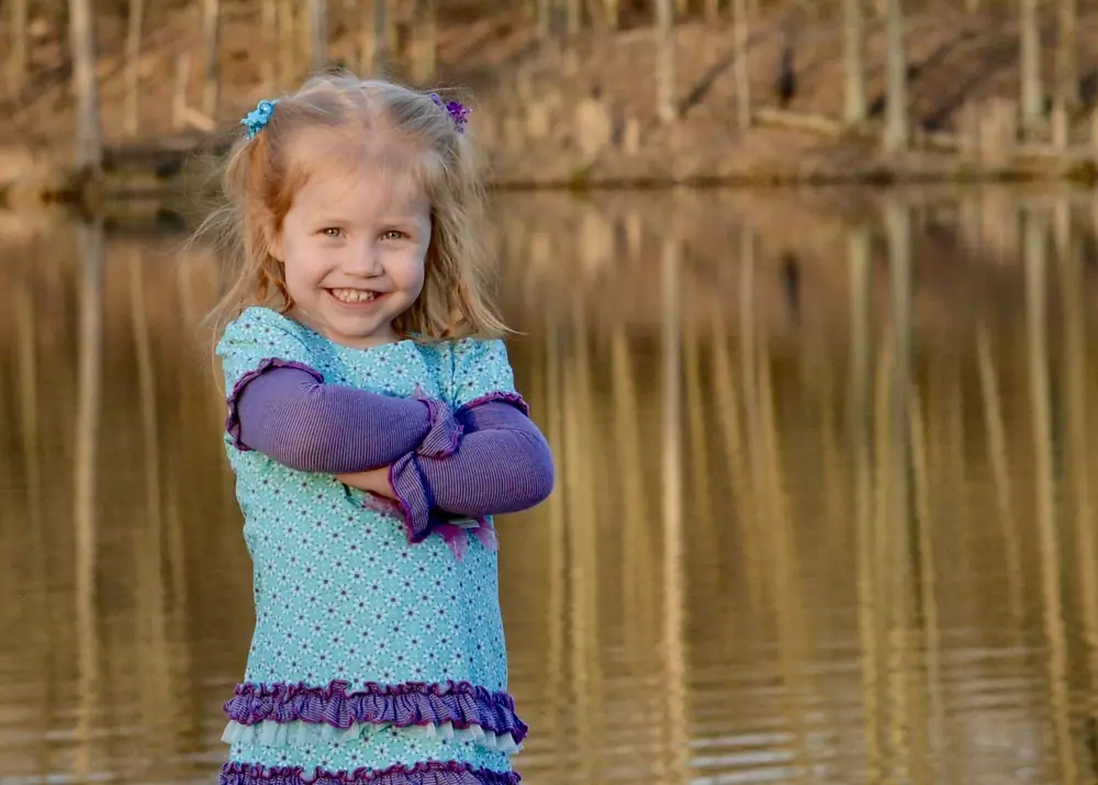 Girl standing beside a pond in autumn