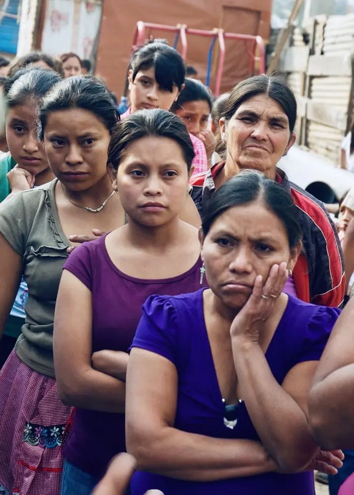 Women waiting in line, one resting her cheek against her hand