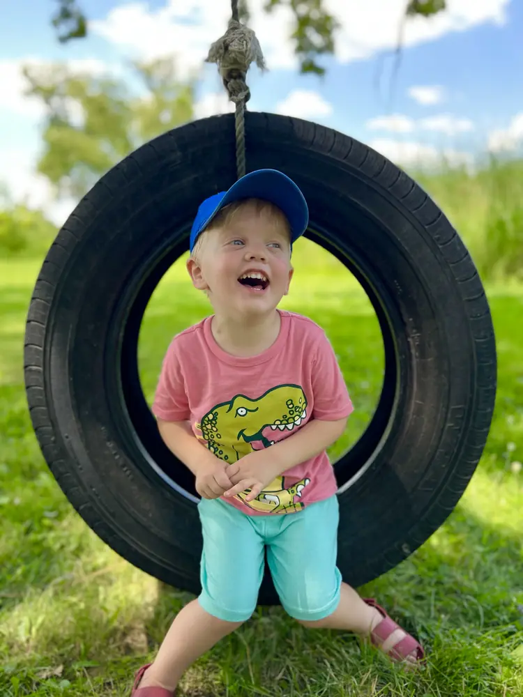 Child sitting inside a tire swing, laughing