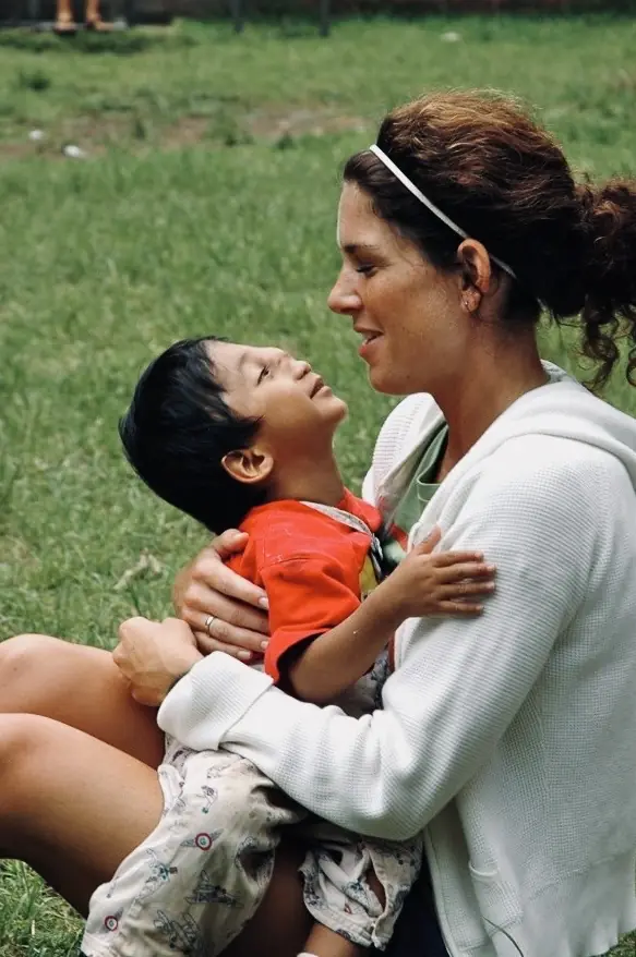 Woman lifting a laughing child on the grass