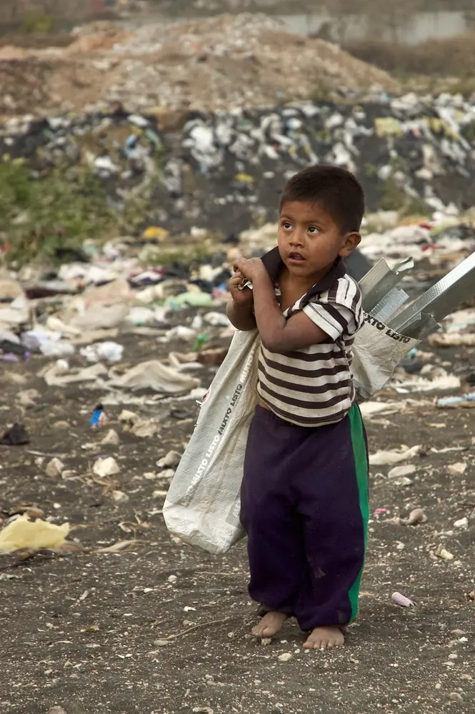 Boy carrying a sack across a dump site