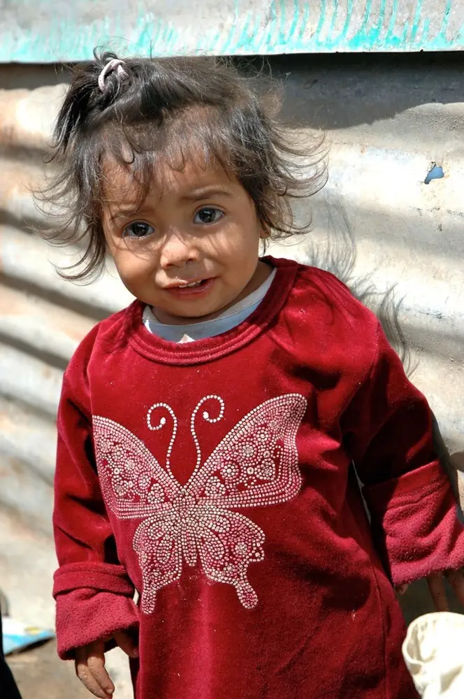 Young girl in a red butterfly sweater against corrugated metal
