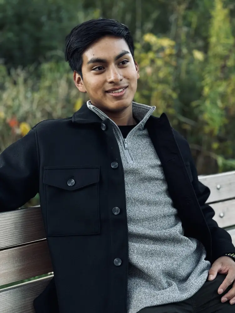 Young man seated on a park bench in autumn
